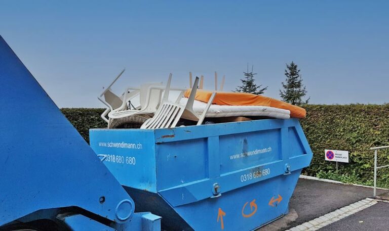 Die mit Bett, Matratze und Plastikstühlen gefüllte Mulde vor dem Abtransport